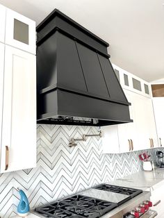 a black stove top oven sitting inside of a kitchen next to white cabinets and drawers