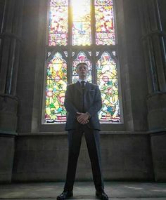 a man standing in front of a stained glass window with his hands on his hips