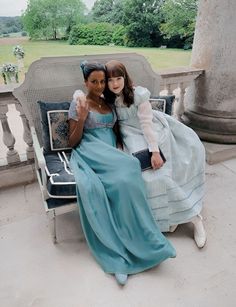 two women sitting on a bench in dresses