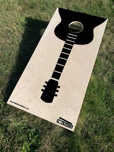 a wooden board with an image of a guitar on it, laying in the grass