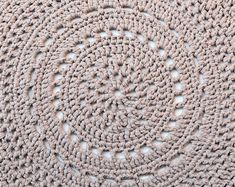 a circular crochet doily is shown in light pink