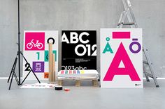 an assortment of art work displayed in front of a wall with ladders and posters