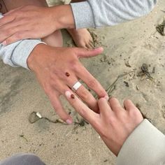 two people holding their hands together on the beach