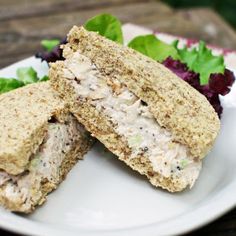 a sandwich cut in half sitting on top of a white plate next to a cucumber