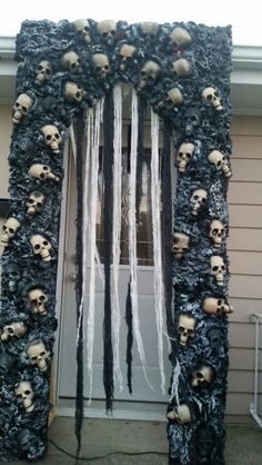 an outdoor halloween decoration with fake skulls and icing on the front door, decorated in black