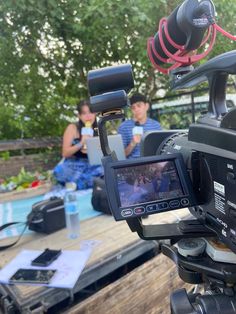 a video camera sitting on top of a wooden table next to a person in a blue shirt