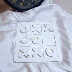 a clock sitting on top of a bed next to a white sheet with holes in it