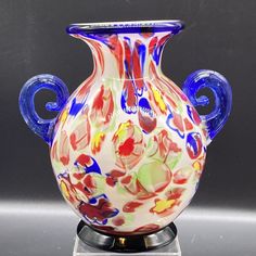 a colorful vase sitting on top of a metal stand