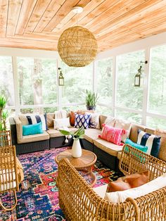 a living room with wicker furniture and colorful pillows on the couches in it