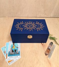 a blue box sitting on top of a wooden table next to cards and a lighter