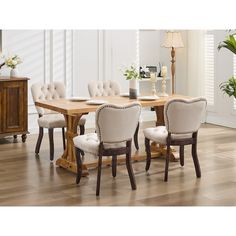 a dining room table and chairs with white upholstered cushions