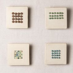 four ceramic tiles with different colored dots on each one and two smaller ones in the middle