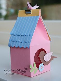 a pink birdhouse with a blue roof