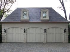 a two car garage with three windows on the top and one above it's doors