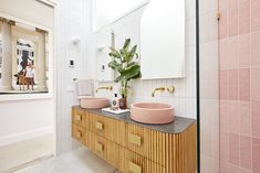 a bathroom with two sinks and a large plant in the mirror on the counter top