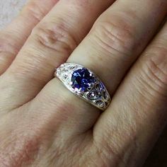 a woman's hand with a ring on it and a blue stone in the middle