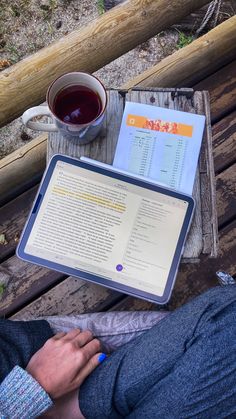 a person sitting at a table with a book and cup of tea