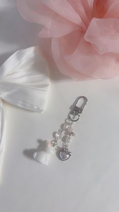 a pink flower and some pearls on a white surface