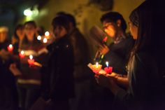 people holding lit candles in their hands at night