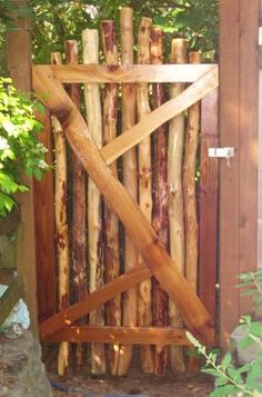 a wooden gate made out of logs in the woods