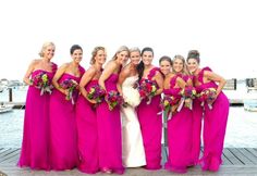 a group of women standing next to each other on a pier with bouquets in their hands