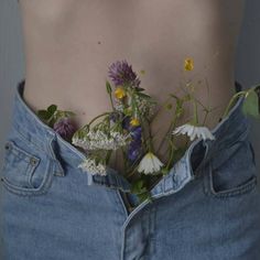 a woman's stomach with flowers in her jeans