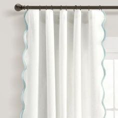 white curtains with scalloped edges hanging on a curtain rod