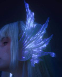 a woman with long blonde hair and blue wings on her head is staring into the distance