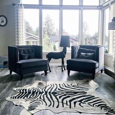 a living room with zebra print rug and two chairs in front of a large window