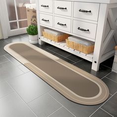 a bathroom with gray tile flooring and white cabinetry next to a beige rug