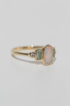 Art deco inspired ring with Australian opal, with either aquamarine and diamonds, or rubies. The opal is inlaid into the elongated hexagon, measuring 9.5mm x 5mm. Accent aquamarine and diamonds are approximately .30 total carat worth. Millimeter measurement from end to end is 15mm. Your choice of gold color and karat. The band is 1.75mm thick. Please leave a note at checkout with your preferred size. All gems and rocks are nuanced in color, please know that your ring will be very similar to the Opal Diamond Ring Engagement, Opal Accent Engagement Ring, Hexagon Opal Ring, Hazel Engagement Ring, Aquamarine Rings Vintage, Diamond Opal Ring, Art Deco Opal Ring, Wedding Ring Art Deco, Opal And Aquamarine Ring