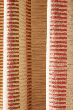 an orange and beige striped curtain with vertical stripes on it's side, closeup