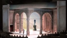 the stage is set for a play with two men standing on pedestals in front of an arch