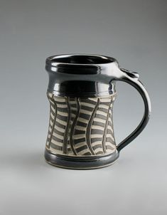 a black and white striped coffee mug on a gray background with the handle extended up