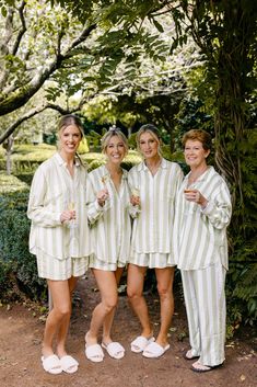 three women in white and green striped pajamas posing for the camera with their thumbs up