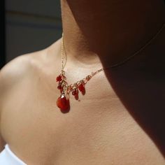 a woman wearing a gold necklace with red beads on it's neck and back