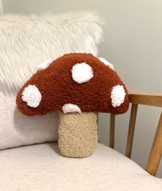 a stuffed mushroom sitting on top of a wooden chair next to a white pillow in a room