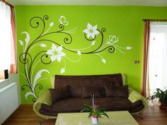 a living room with green walls and white flowers painted on the wall above the couch