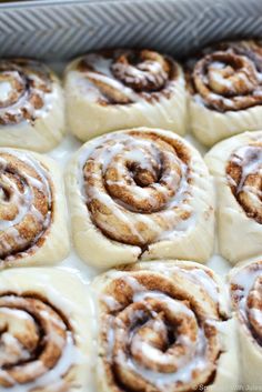 cinnamon rolls with icing sitting in a pan