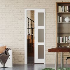 a living room filled with furniture and a book shelf next to a white brick wall