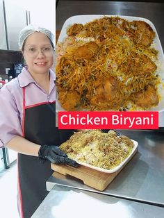 a woman in an apron is holding up a tray of chicken biriyani