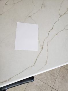 a white marble table top with a piece of paper stuck to the edge of it