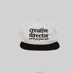 a white and black hat with the words creative director printed on it's side