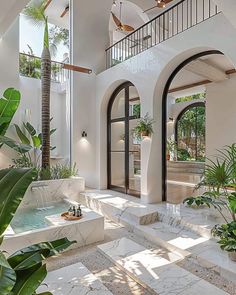 the inside of a house with an indoor fountain in the center and potted plants on either side