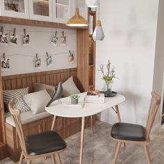 a white table with two black chairs and pictures on the wall