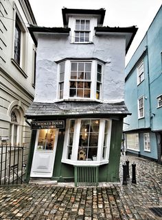 an old cobblestone street in front of a building with a green door and window