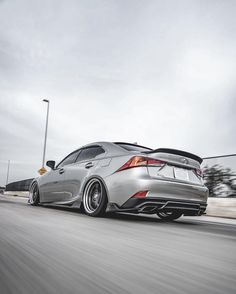 the rear end of a silver car driving down a road