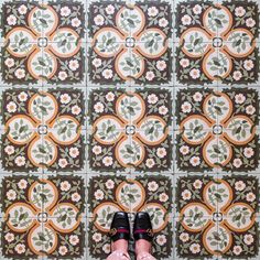 a person standing in front of a tiled wall with their feet propped up on the floor