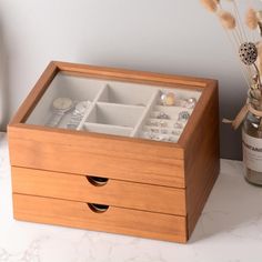 a wooden jewelry box with drawers on a table next to some dried flowers and a bottle