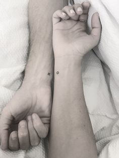 two hands holding each other with small tattoos on their wrists and wrist, both showing the same